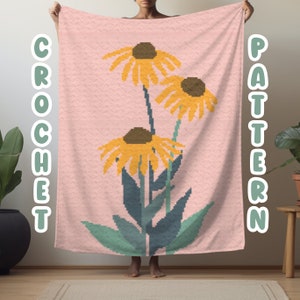 Op de afbeelding: Een roze gehaakt patroon deken met een gepixeld bloemmotief. Het heeft gele bloemen, bruine centra en groene bladeren. De tekst "CROCHET" en "PATTERN" staat in groen en wit.