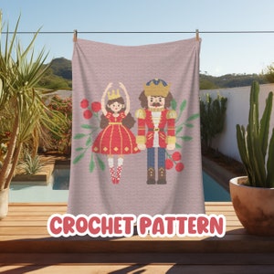 May include: Crochet pattern for a Nutcracker and a ballerina. The pattern features a pink background with red berries and green leaves. The Nutcracker is wearing a red and gold uniform, and the ballerina is wearing a red dress with a gold crown.