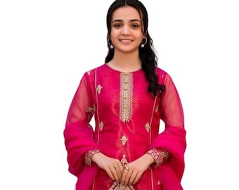 Op de afbeelding: Een levendig fuchsia driedelig ensemble met een tuniek met lange mouwen, voorzien van gouden borduursels langs de halslijn en zoom, gecombineerd met een wijde broek en een bijpassende transparante sjaal met gouden draaddetails.