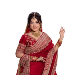 May include: A deep red saree featuring intricate gold embroidery along the borders and hem. The garment includes a matching short-sleeved blouse with detailed gold patterns, a draped pallu, and gold-toned jewellery including bangles and a necklace.