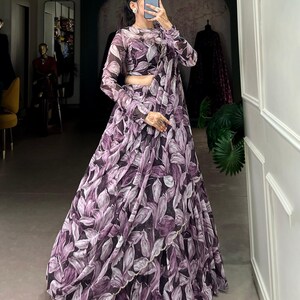 May include: A purple and white floral print maxi skirt with a matching crop top. The skirt has a ruffled hem and the top has long sleeves.