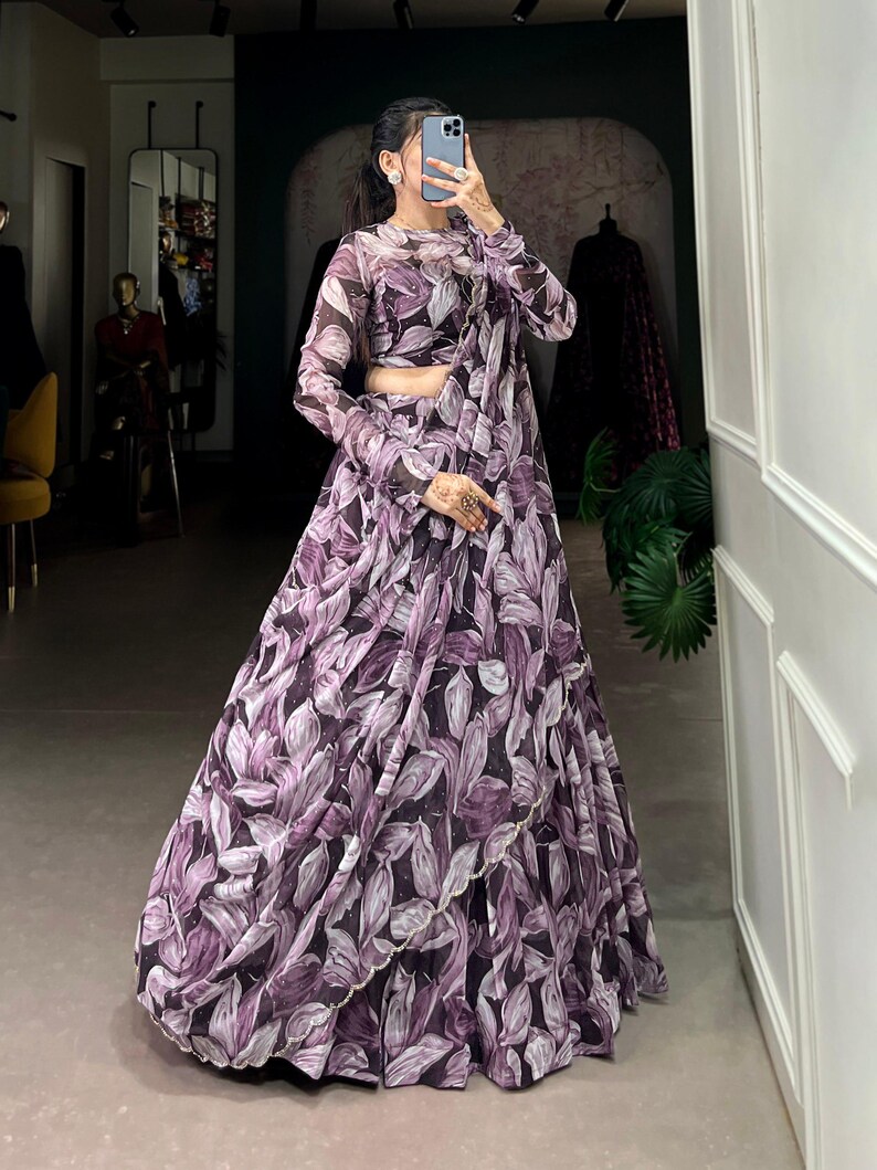 May include: A purple and white floral print maxi skirt with a matching crop top. The skirt has a ruffled hem and the top has long sleeves.