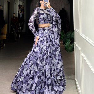 May include: A purple and white floral print maxi skirt with a matching long-sleeved top. The skirt has a flowing, A-line silhouette.