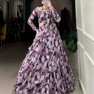 May include: A purple and white floral print maxi skirt with a ruffled hem. The skirt is made of a sheer fabric and has a flowing silhouette.