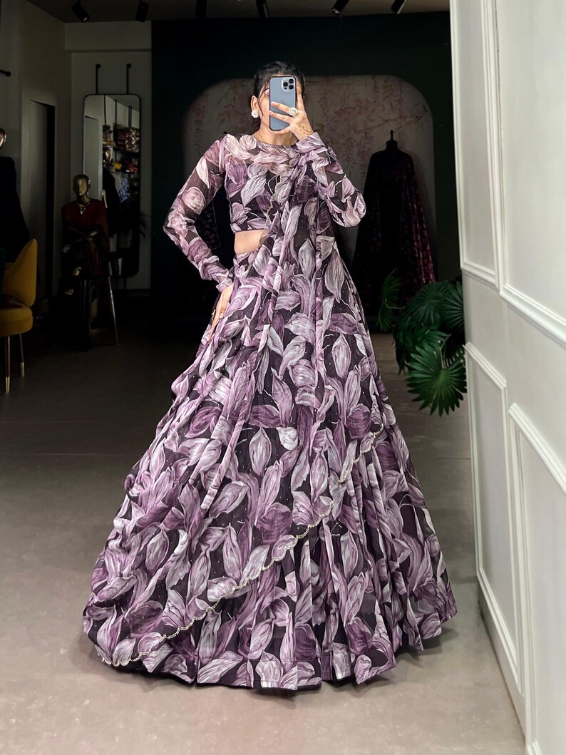 May include: A purple and white floral print maxi skirt with a ruffled hem. The skirt is made of a sheer fabric and has a flowing silhouette.