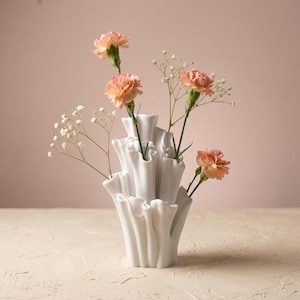Matte white textured coral vase holding peach carnations and white baby's breath on a soft beige background. A textured vase for dried or fresh flowers, about 7.2 in tall.