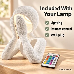 Graphic reading Included With Your Lamp, listing Lighting, Remote control and Wall plug, with a USB powered note, showing the matte textured white sculpture lamp and a colorful remote on a wooden table.