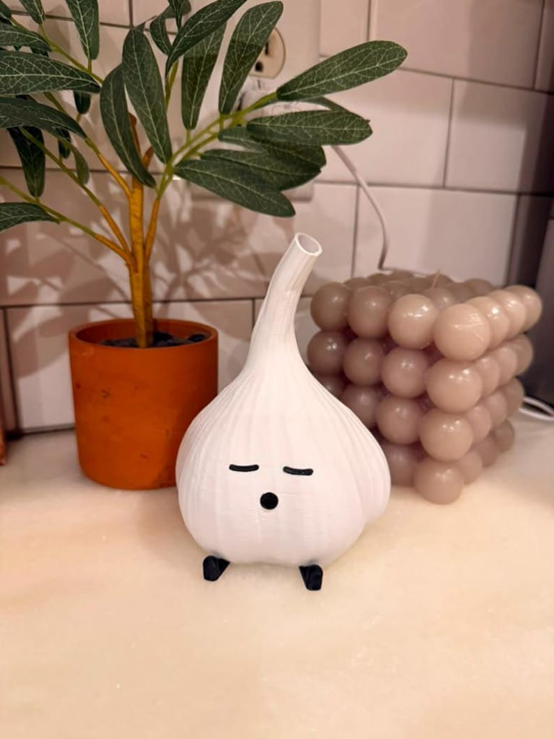 Unlit white garlic lamp on a kitchen counter with a plant, tile, and a white cable