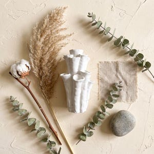 Matte white textured coral vase styled on beige linen with dried pampas grass, a cotton stem and eucalyptus sprigs. A natural boho coral vase for dried flowers, about 7.2 in tall.