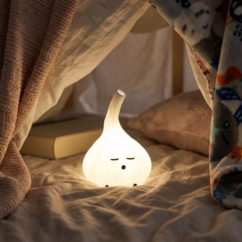 Warm glowing garlic lamp tucked into a blanket with a book behind it