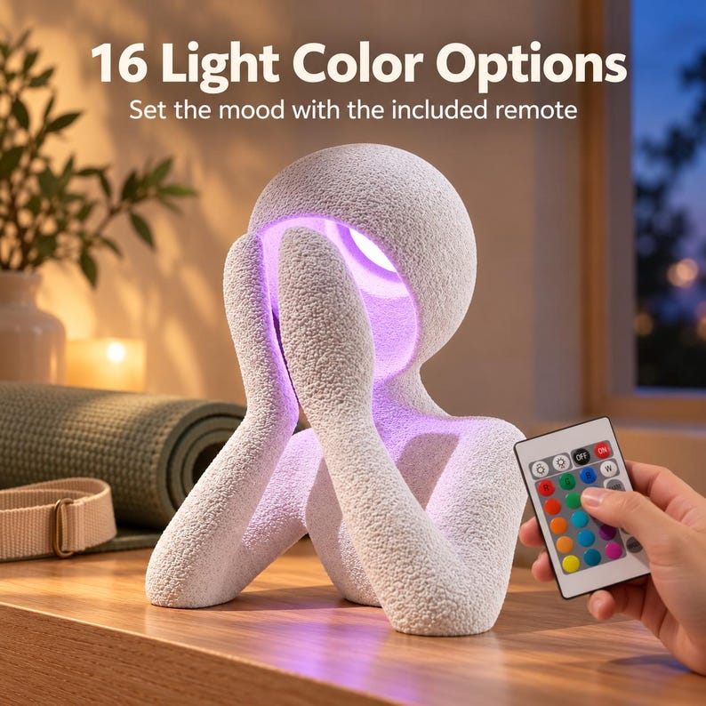 Night light with a matte textured white figure glowing soft purple, held beside a hand pointing a colorful light remote, on a wooden shelf with a window behind and text reading Light Color Options.