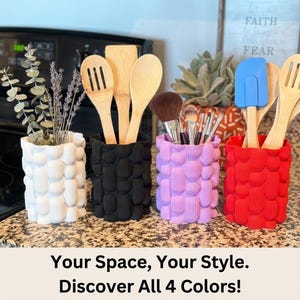 Four textured matte vases in white, black, lavender and red holding wooden utensils, brushes and dried stems on a kitchen counter, with the text "Your Space, Your Style. Discover All 4 Colors!"