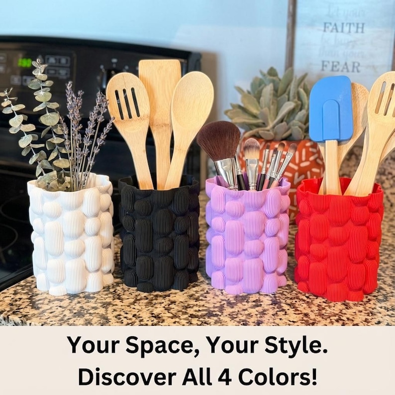 Four textured matte vases in white, black, lavender and red holding wooden utensils, brushes and dried stems on a kitchen counter, with the text "Your Space, Your Style. Discover All 4 Colors!"