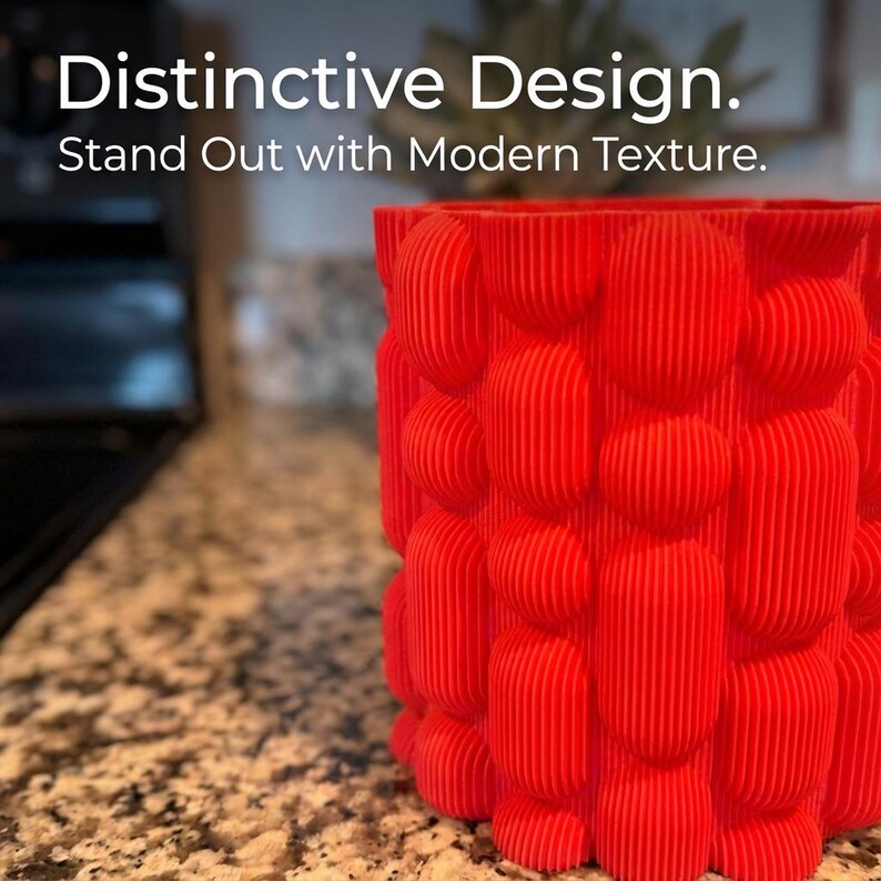 Close view of a textured matte red vase on a speckled brown kitchen counter, with the text "Distinctive Design. Stand Out with Modern Texture."
