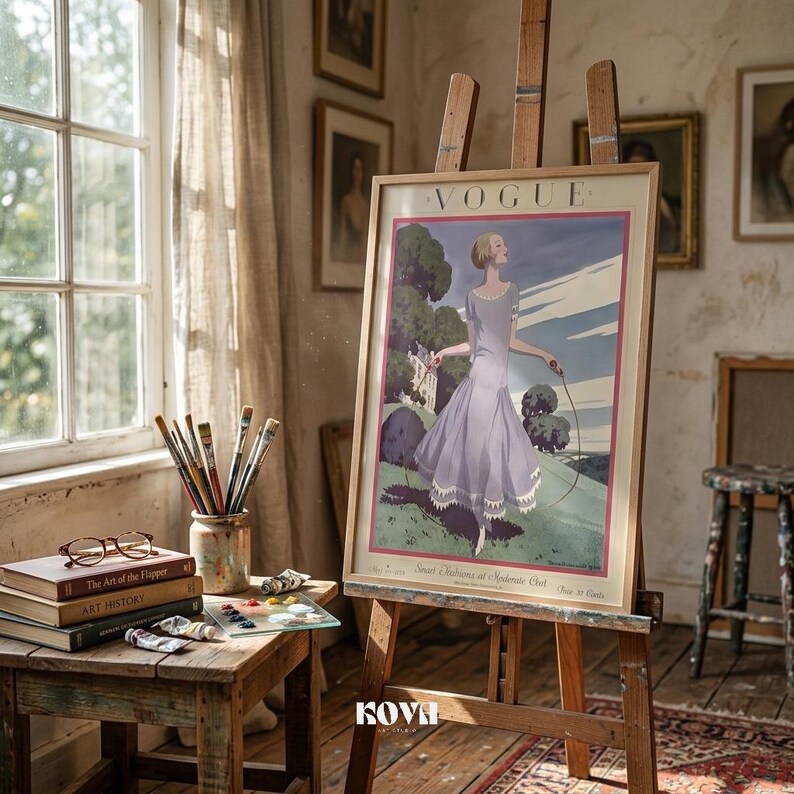 May include: A framed vintage Vogue magazine cover print on an easel. The artwork features a woman in a lavender dress, holding a rope, with a green landscape background. The scene is set in a room with a window, paintbrushes, and art supplies.