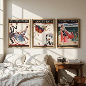 Op de afbeelding: Drie ingelijste vintage covers van het tijdschrift "Vanity Fair". De kunstwerken tonen kleurrijke illustraties van mensen in verschillende scènes, waaronder een man op een schommelpaard, figuren in de lucht en een strandscène. De frames zijn goudkleurig.