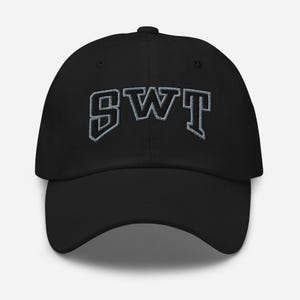 May include: Black baseball cap with the embroidered letters "SWT" in a stylized, blocky font. The letters are outlined in a lighter color, creating a contrast against the cap's dark fabric. The cap has a curved brim and an adjustable strap.