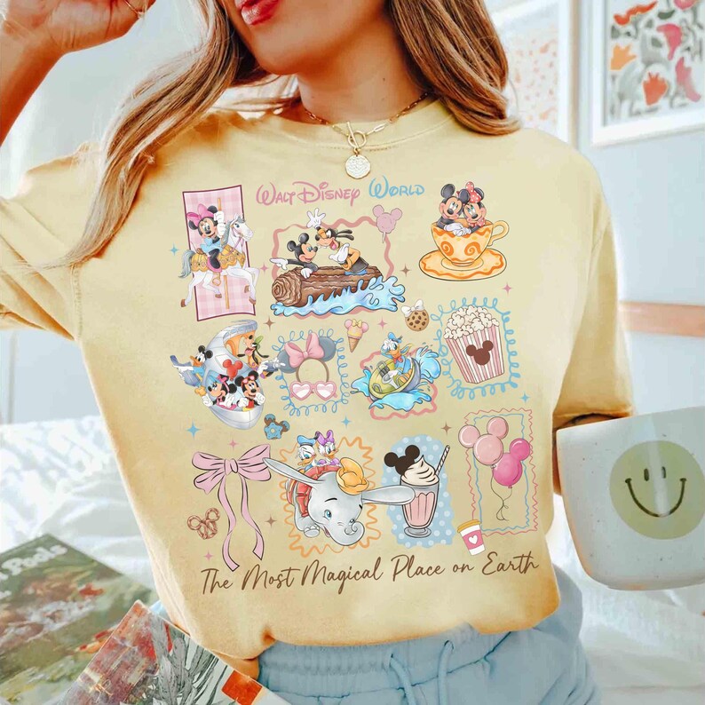 May include: Yellow t-shirt featuring various Disney characters and icons, including Mickey and Minnie Mouse, Dumbo, and popcorn. The shirt has the text "Walt Disney World" and "The Most Magical Place on Earth."