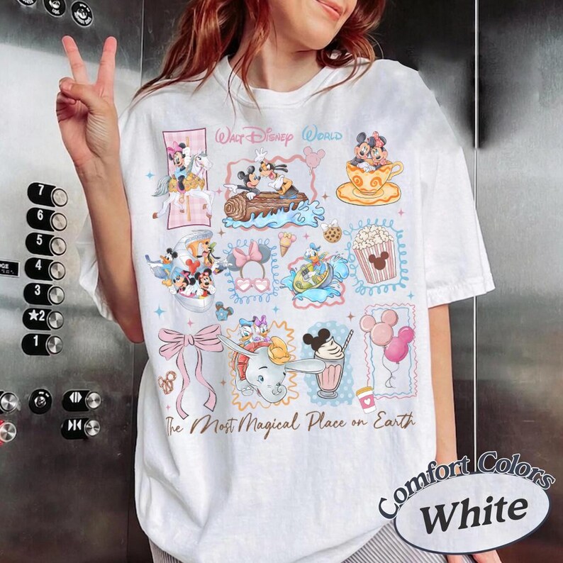 May include: White t-shirt with colorful Disney character graphics. Features Mickey and Minnie Mouse, Donald Duck, and Dumbo. Text includes "Walt Disney World" and "The Most Magical Place on Earth."