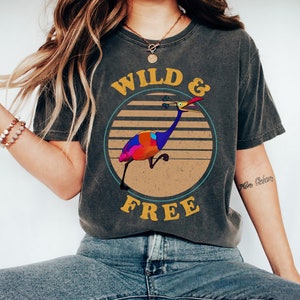 May include: A dark gray t-shirt with a vintage-style graphic of a colorful bird with the text "WILD & FREE" in yellow.