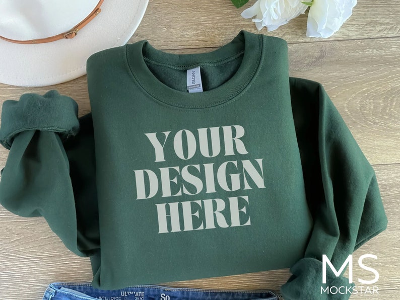 Puede incluir: Una sudadera verde oscuro con el texto "YOUR DESIGN HERE" impreso en blanco en la parte delantera.