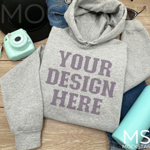 May include: A gray hooded sweatshirt with the text "YOUR DESIGN HERE" printed in purple on the front.