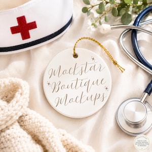 May include: A round white ceramic ornament with a gold string, featuring the brown cursive text Mockstar Boutique Mockups and small star icons, displayed alongside a white nurse cap with a red cross and a dark blue medical stethoscope.