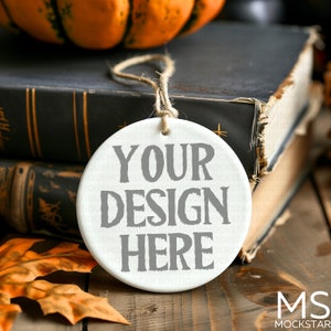 May include: White ceramic ornament with a string for hanging. The ornament has the text "YOUR DESIGN HERE" printed in gray.