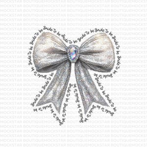 May include: A silver glitter bow with a large iridescent jewel in the center. The bow is surrounded by the text "Bride to be" repeated multiple times.