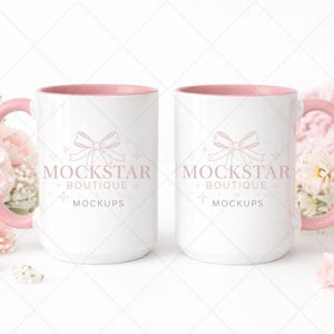 May include: Two white ceramic mugs with pink handles and interiors. Each mug features a bow design and the text "MOCKSTAR BOUTIQUE MOCKUPS" in light pink. The mugs are surrounded by pink flowers and a pink knitted blanket.