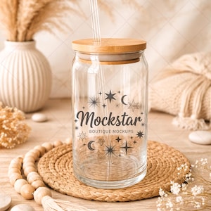 Può includere: Un barattolo di vetro trasparente con coperchio in legno e cannuccia trasparente. Il barattolo presenta un design grafico nero con stelle, lune e il testo "Mockstar Boutique Mockups". Il barattolo è posto su un tappetino intrecciato.