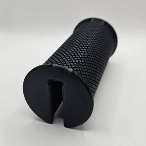 Puede incluir: Empuñadura negra impresa en 3D con una superficie texturizada y una ranura en la parte inferior.