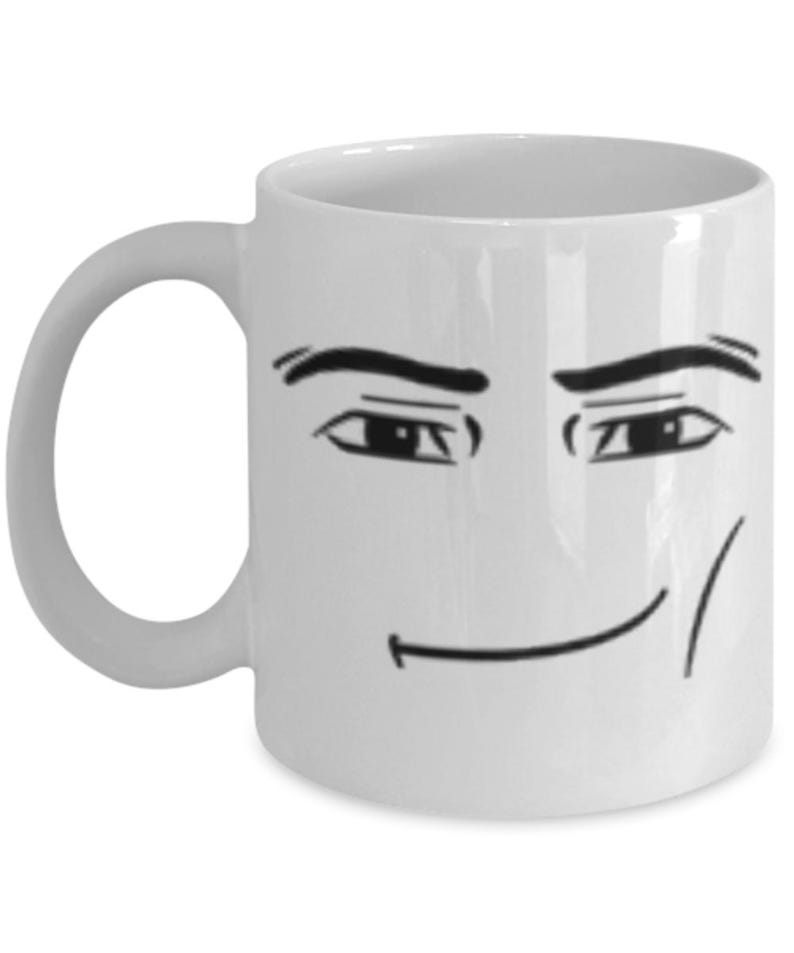 May include: White ceramic coffee mug with a black and white illustration of a face with a smirk. The face has eyebrows, eyes, and a slight smile.