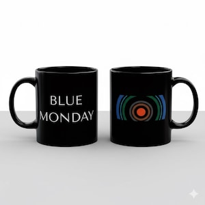 Puede incluir: Dos tazas de cerámica negras. Una taza presenta el texto "BLUE MONDAY" en blanco. La otra taza tiene un diseño gráfico con círculos concéntricos en naranja, gris y verde. Ambas tazas tienen un asa curva.