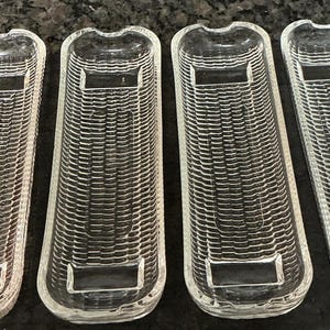 May include: Four clear glass rectangular trays with rounded ends, featuring a textured ribbed pattern across the surface and smooth, flat rectangular sections at both ends. Each tray has a small notched cutout at the top center edge.