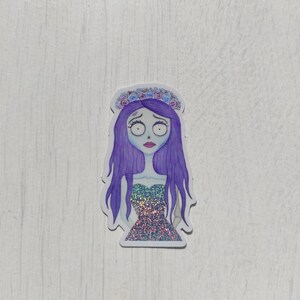 K&ouml;nnte beinhalten: Ein Aufkleber mit einer Cartoon-Illustration eines M&auml;dchens mit lila Haaren, das eine Blumenkrone und ein glitzerndes Kleid tr&auml;gt. Das M&auml;dchen hat einen traurigen Gesichtsausdruck.