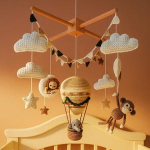 May include: A handmade baby mobile featuring crochet clouds, stars, and animal figures. The mobile includes a hot air balloon with an elephant, a lion in a crescent moon, and a monkey. The color palette is soft, with cream, brown, and tan tones.