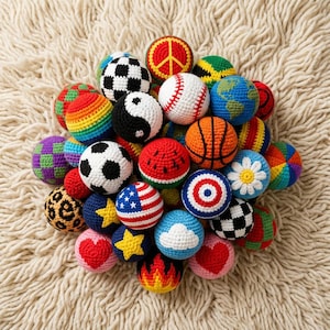 May include: A collection of colorful, crocheted balls with various designs, including a soccer ball, baseball, basketball, and a peace sign. Other designs include a watermelon, a yin-yang symbol, and a globe. The balls are arranged on a cream-colored, textured surface.