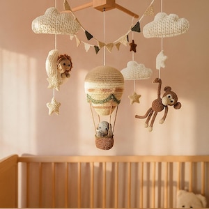 May include: A handmade crochet baby mobile featuring a hot air balloon, clouds, stars, a lion in a crescent moon, and a monkey. The mobile is suspended above a wooden crib, creating a whimsical nursery decor.