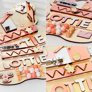 May include: A wooden activity board for children with a pink and white color scheme. The board features a variety of activities, including a clock, a bead maze, a shape sorter, a zipper, a latch, and a mirror. The board is personalized with the name "Lottie".