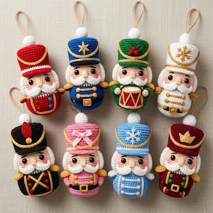 Könnte beinhalten: Acht gehäkelte Nussknacker-Ornamente mit Aufhängeschlaufen. Die Figuren haben verschiedene Farben wie Rot, Blau, Grün, Weiß, Schwarz, Rosa und Kastanienbraun, jeweils mit detaillierten Hüten, weißen Schnurrbärten und goldfarbenen Akzenten an den Uniformen.