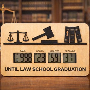 May include: Wooden countdown timer with a law theme. Features a gavel, scales of justice, and books. The digital display shows 998 days, 23 hours, 59 minutes, and 37 seconds until law school graduation. The text "UNTIL LAW SCHOOL GRADUATION" is printed below the display.