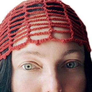 May include: A rust-colored crochet head covering featuring an open, grid-like pattern. The accessory is constructed from yarn and displays a scalloped edge along the bottom. The text "Crochet pattern" is visible in the upper left corner.
