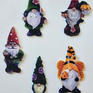 May include: Five colorful gnome buttons with different designs. The gnomes are wearing hats and have white beards. The buttons are made of ceramic and have a glossy finish.