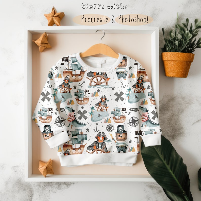 May include: A white sweatshirt with a repeating pattern of watercolor illustrations of pirates, ships, anchors, and stars. The text "Works with: Procreate & Photoshop!" is printed at the top of the image.