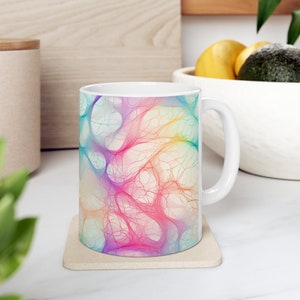 May include: White ceramic mug with a colourful abstract design featuring a network of lines and swirls in shades of pink, blue, yellow, and green.