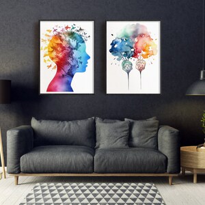 May include: Two framed watercolor paintings on a dark gray wall. The painting on the left depicts a colorful silhouette of a person's head with butterflies. The painting on the right depicts two colorful trees with roots that resemble brains.
