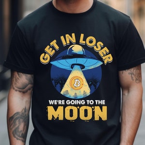 May include: Black t-shirt with a graphic of a UFO with a Bitcoin symbol inside. The text "Get in Loser We're Going to the Moon" is printed on the shirt.