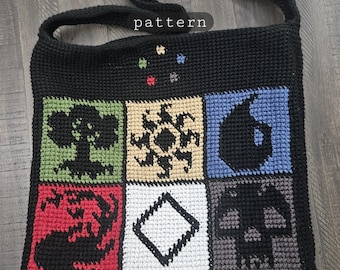 May include: Black crochet shoulder bag with a square design featuring various colorful geometric shapes and symbols. The word "pattern" is visible on the top of the bag. The bag has a long strap for carrying.