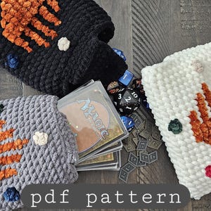 Puede incluir: Bolsas de ganchillo para cartas y dados en negro, gris y blanco, cada una con un diseño de mano naranja y acentos coloridos. Las bolsas están llenas de cartas, dados y fichas. El texto "pdf pattern" está en la parte inferior de la imagen.